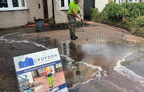 Worker jet washing driveway