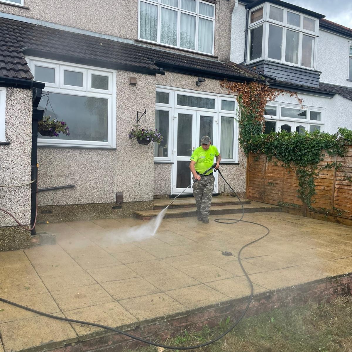 Worker pressure washing patio