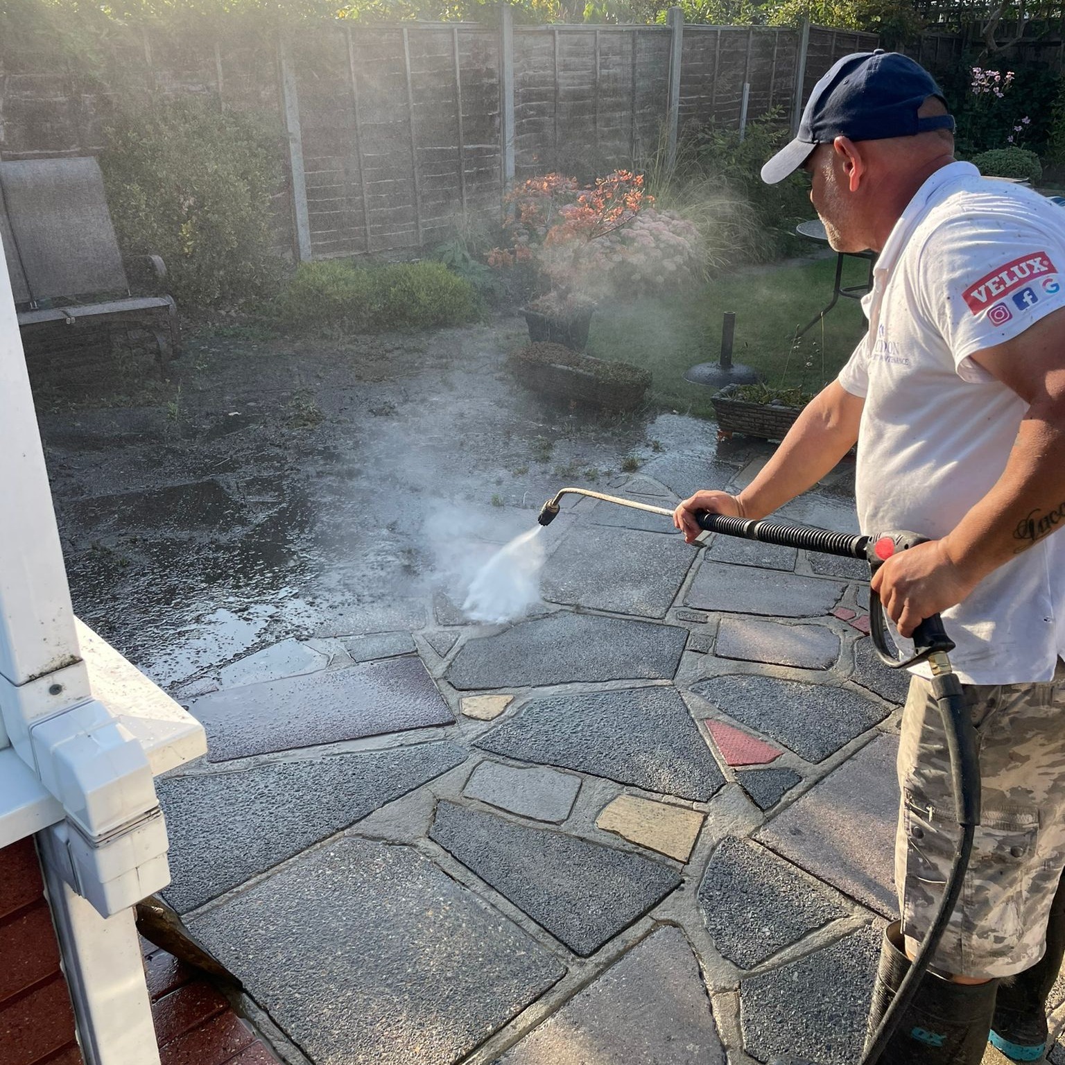 Worker jet washing crazy paving