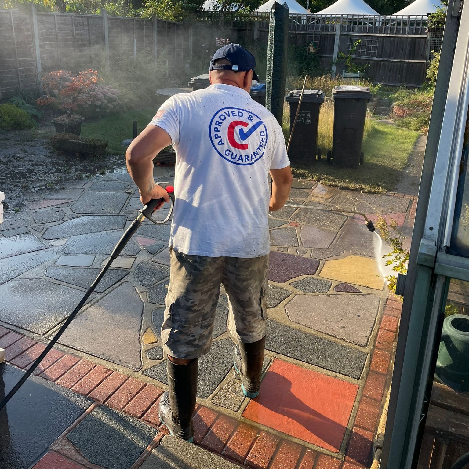 Worker jet washing crazy paving